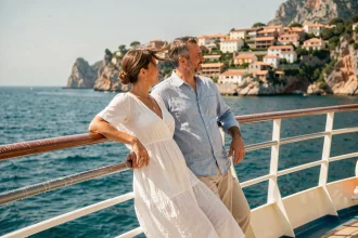 Couple de voyageurs admirant la côte méditerranéenne depuis le pont avant d'un bateau de croisière